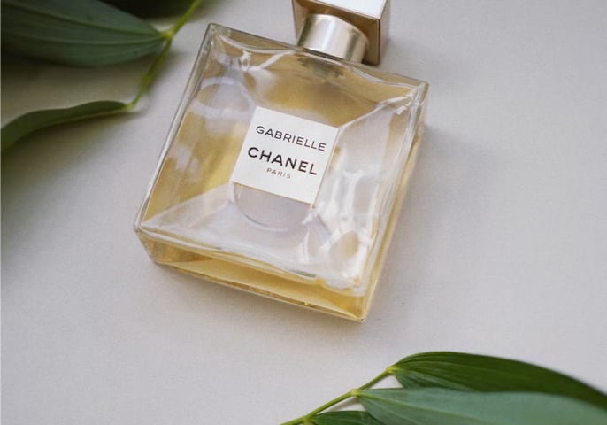 Image of a bottle of Chanel perfume framed by a couple of green leaves.